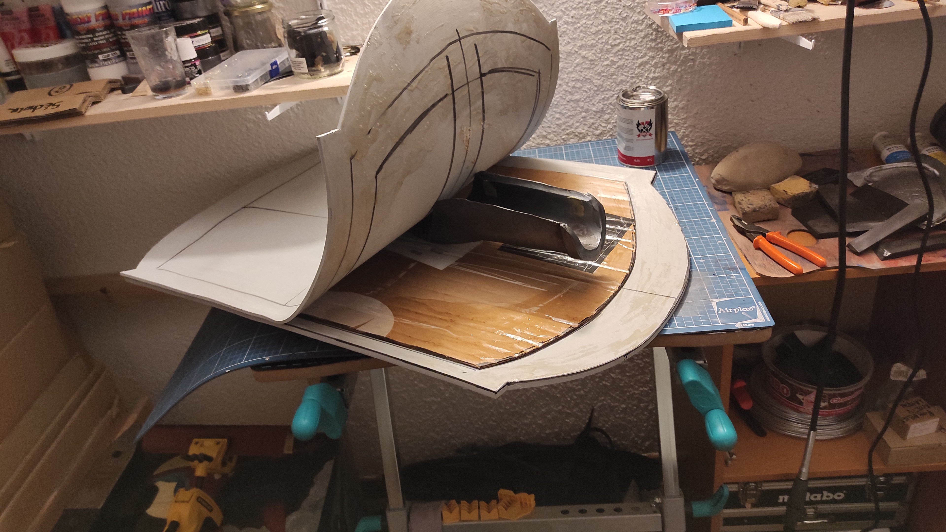 To sew shield's parts (I wanted to have a cardboard inside to force its curvature and enhance its resistance), I used a contact cement, which needed to dry out first. The old armor piece test in the middle prevents parts from sticking together before that