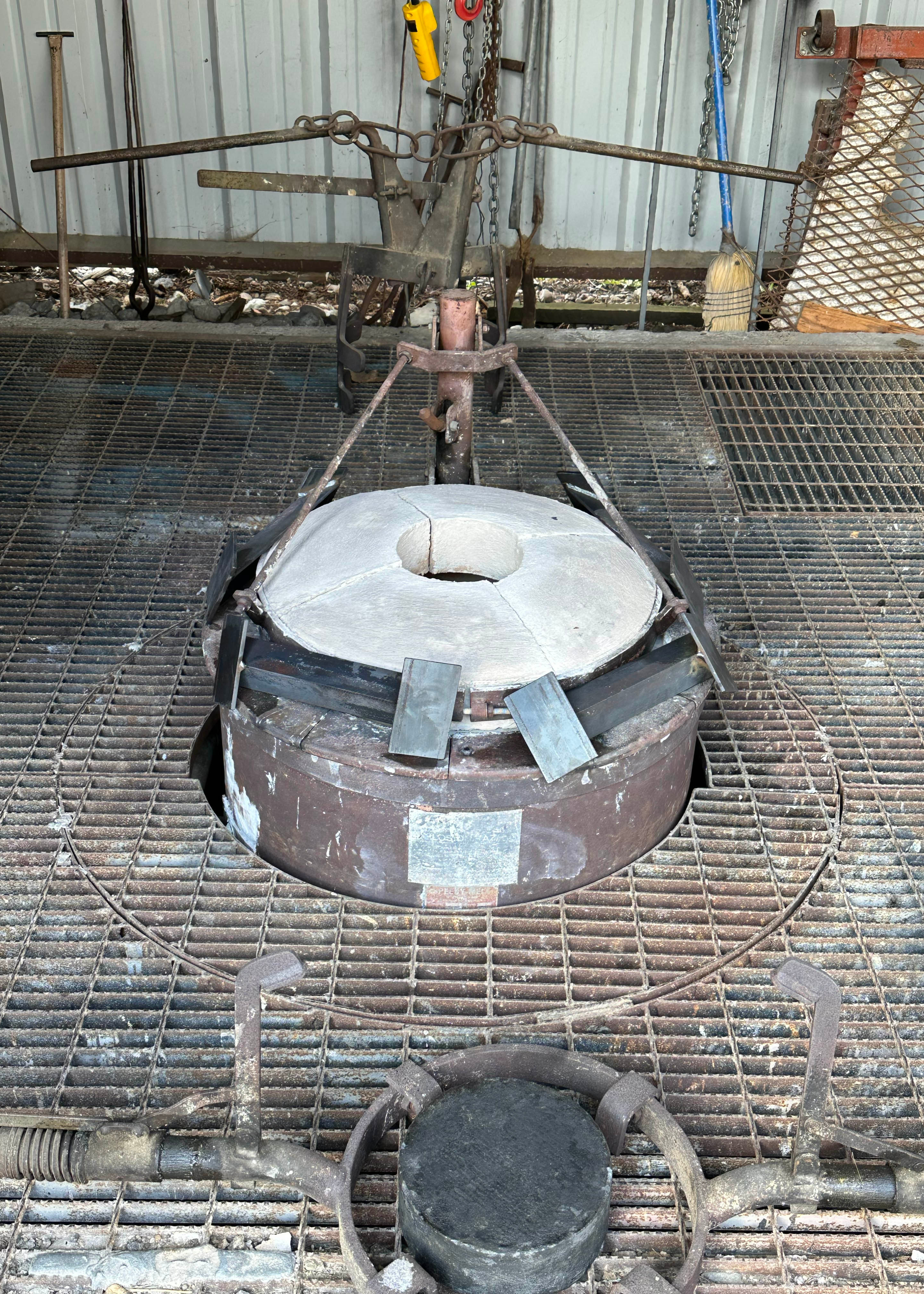 The furnace, the pieces of metal resting on the sides are ingot molds for excess bronze to be poured into.